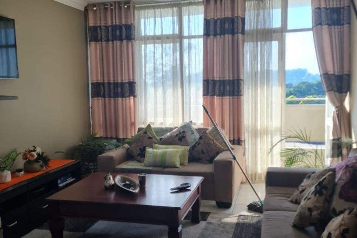 A comfortable living room featuring tiled flooring, a ceiling fan, and large sliding glass doors that provide access to an outdoor balcony area.