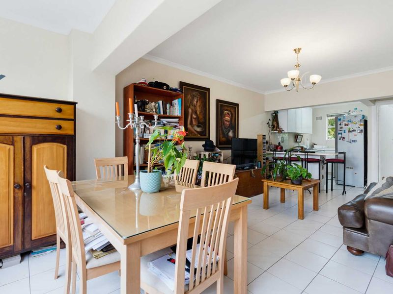 Open-plan living and dining area featuring tiled flooring and a connected kitchen space with a breakfast bar island.