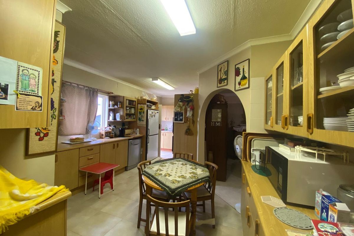 A functional kitchen featuring light wood cabinetry, tiled flooring, and an arched doorway leading to adjacent living spaces.