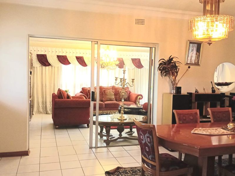 Open plan living and dining area featuring tiled flooring and a sliding glass door connecting to an adjacent lounge space.