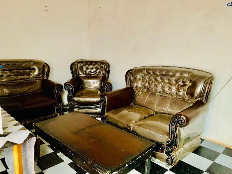 A living room area featuring checkered tile flooring and plain walls, currently requiring cosmetic updates and maintenance to improve the overall aesthetic.