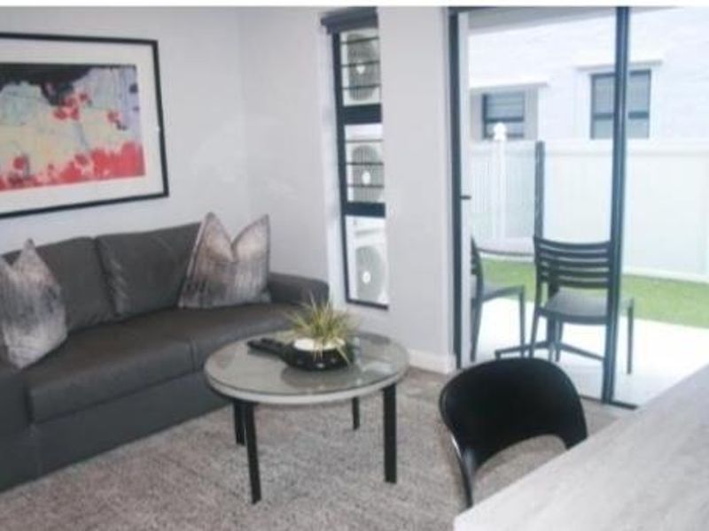 A living room featuring a sliding glass door with access to an outdoor patio area and integrated air conditioning units.