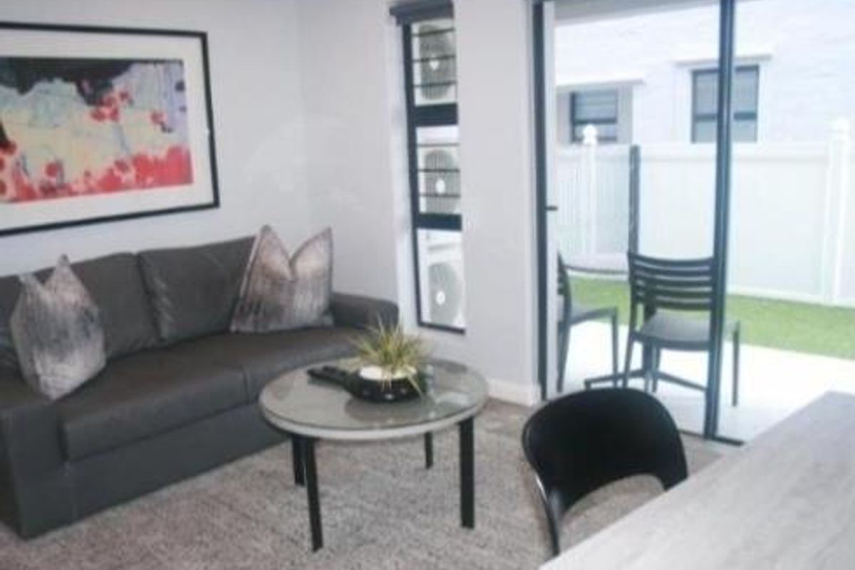A living room featuring a sliding glass door with access to an outdoor patio area and integrated air conditioning units.