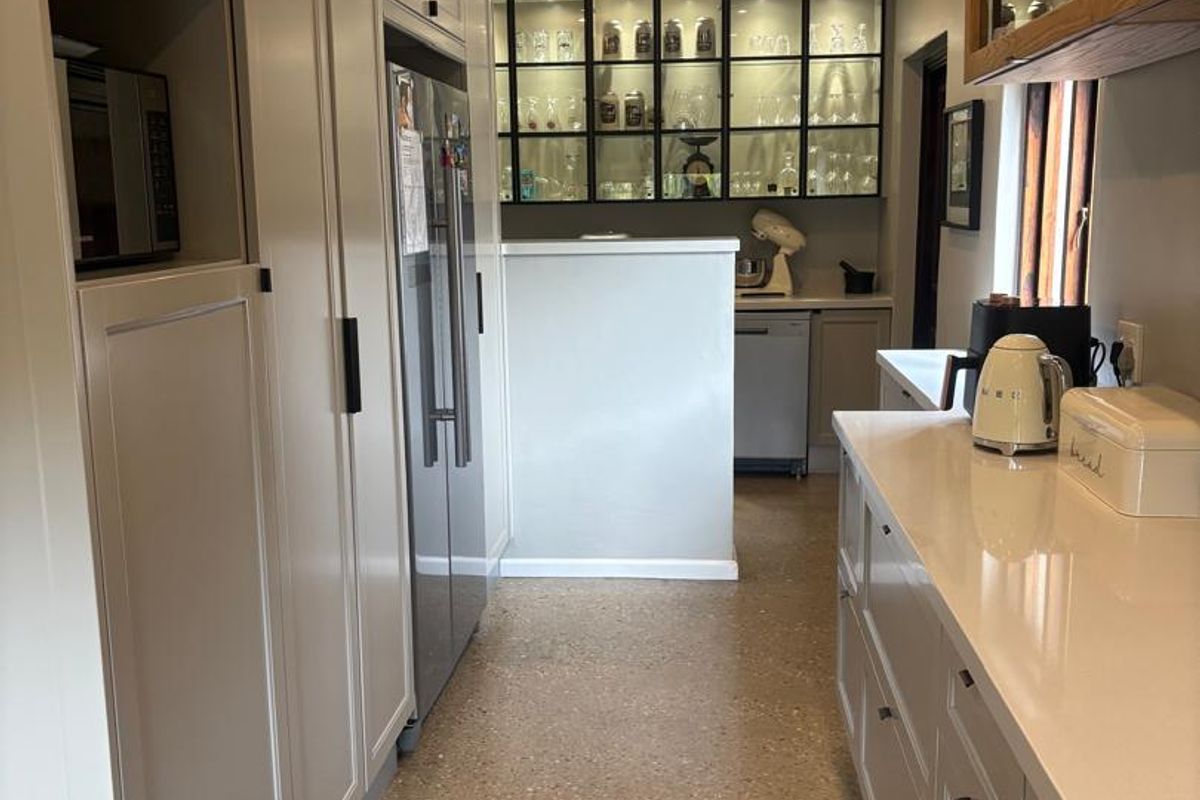Modern kitchen featuring sleek cabinetry, quartz countertops, terrazzo flooring, and elegant glass-front display cabinets with integrated lighting.