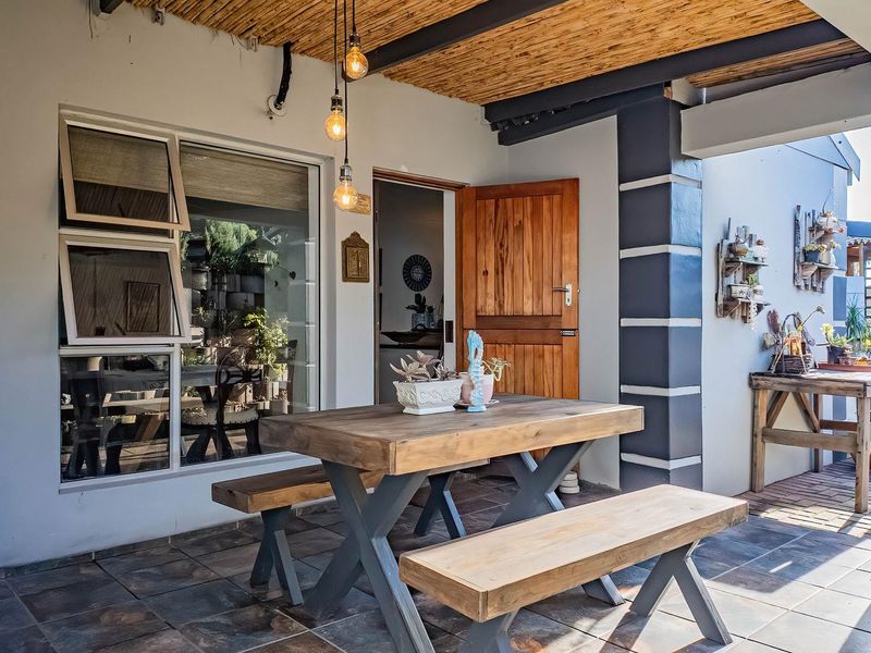 A covered patio area featuring a thatched roof, tiled flooring, and direct access to the home through a timber door.