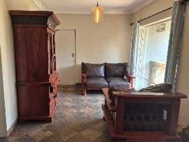 A living room featuring tiled flooring, ceiling cornice, and a sliding glass door providing access to the exterior.