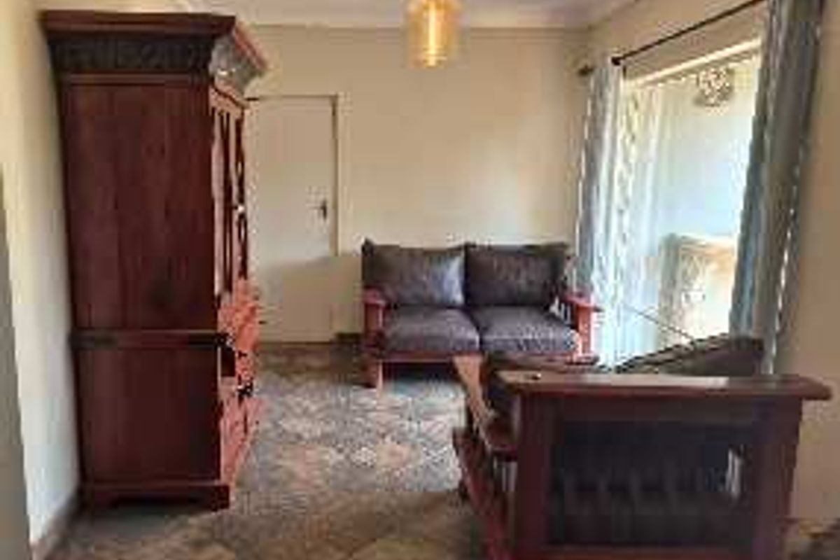 A living room featuring tiled flooring, ceiling cornice, and a sliding glass door providing access to the exterior.