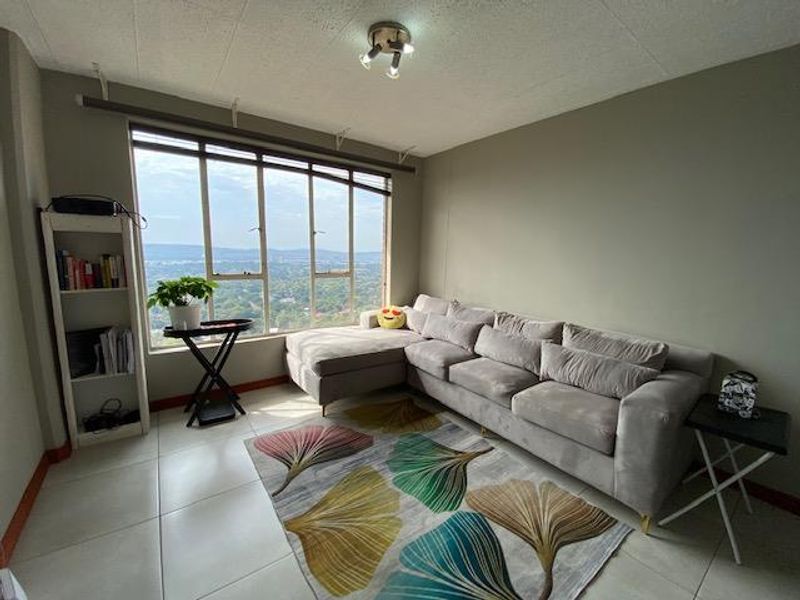 A living room featuring large windows with expansive views, tiled flooring, and a ceiling-mounted spotlight fixture.