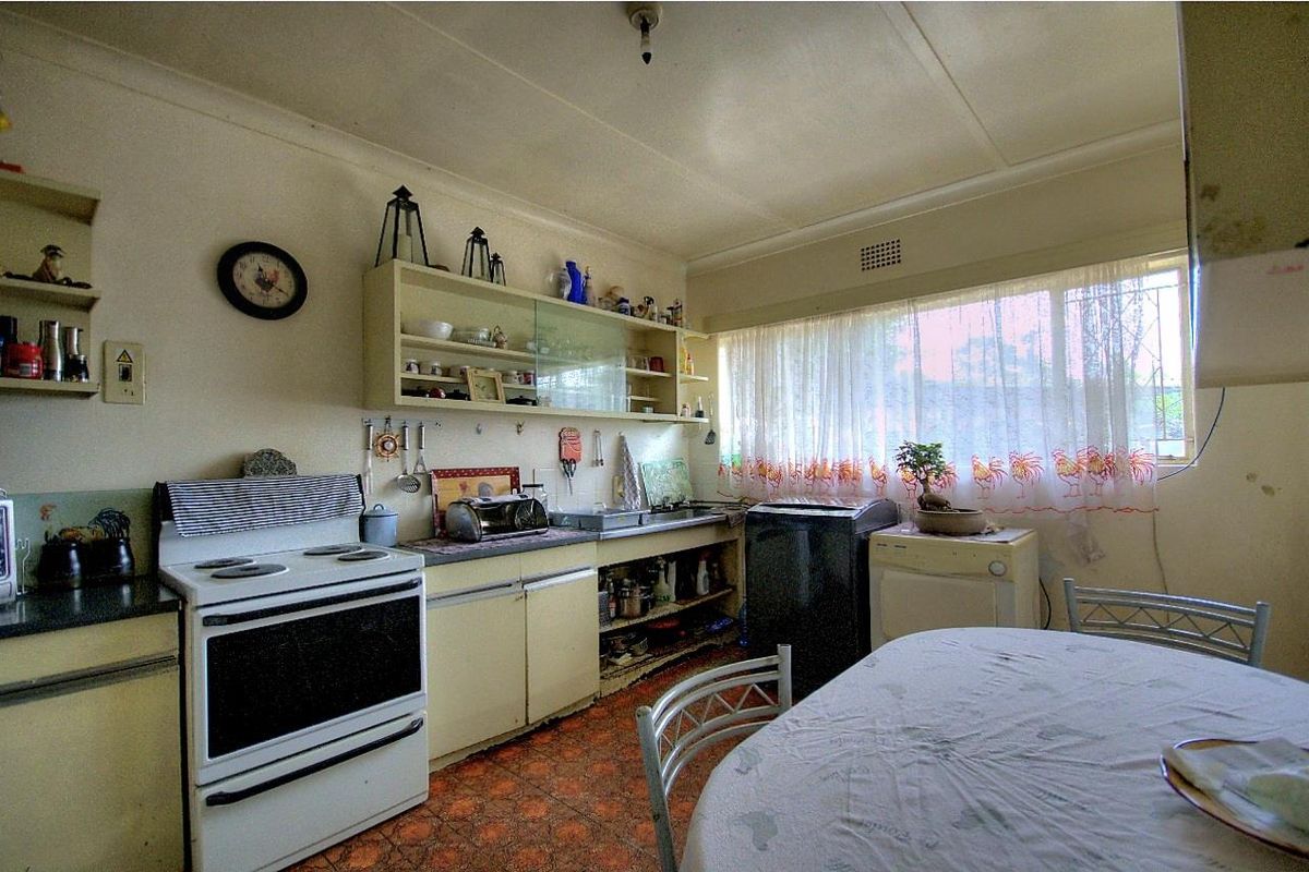 A dated kitchen featuring original cabinetry, a freestanding stove, and patterned tile flooring, offering potential for a modern renovation.