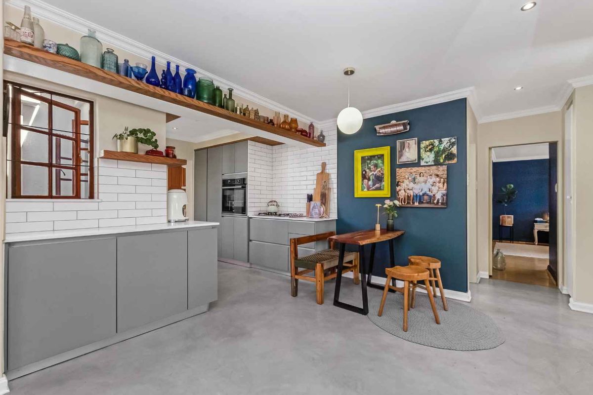 Modern kitchen featuring grey cabinetry, white subway tile backsplash, built-in oven, gas hob, and polished concrete flooring with an open-plan layout.