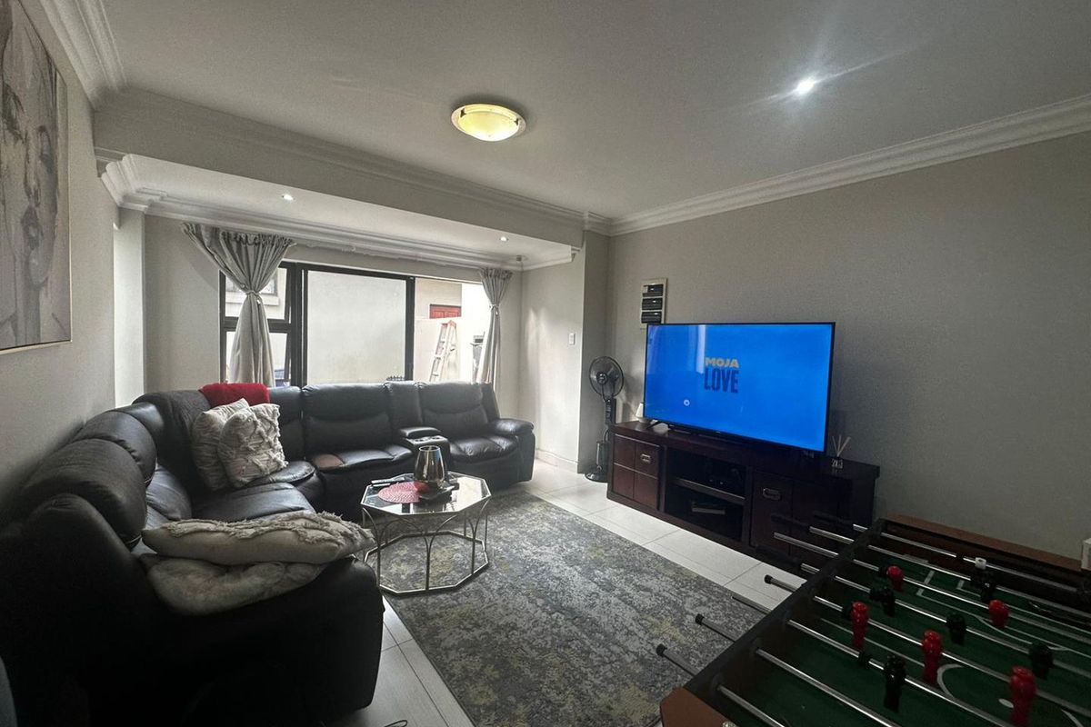 A comfortable living room featuring tiled flooring, recessed ceiling lighting, and large sliding glass doors that provide access to the outdoor area.