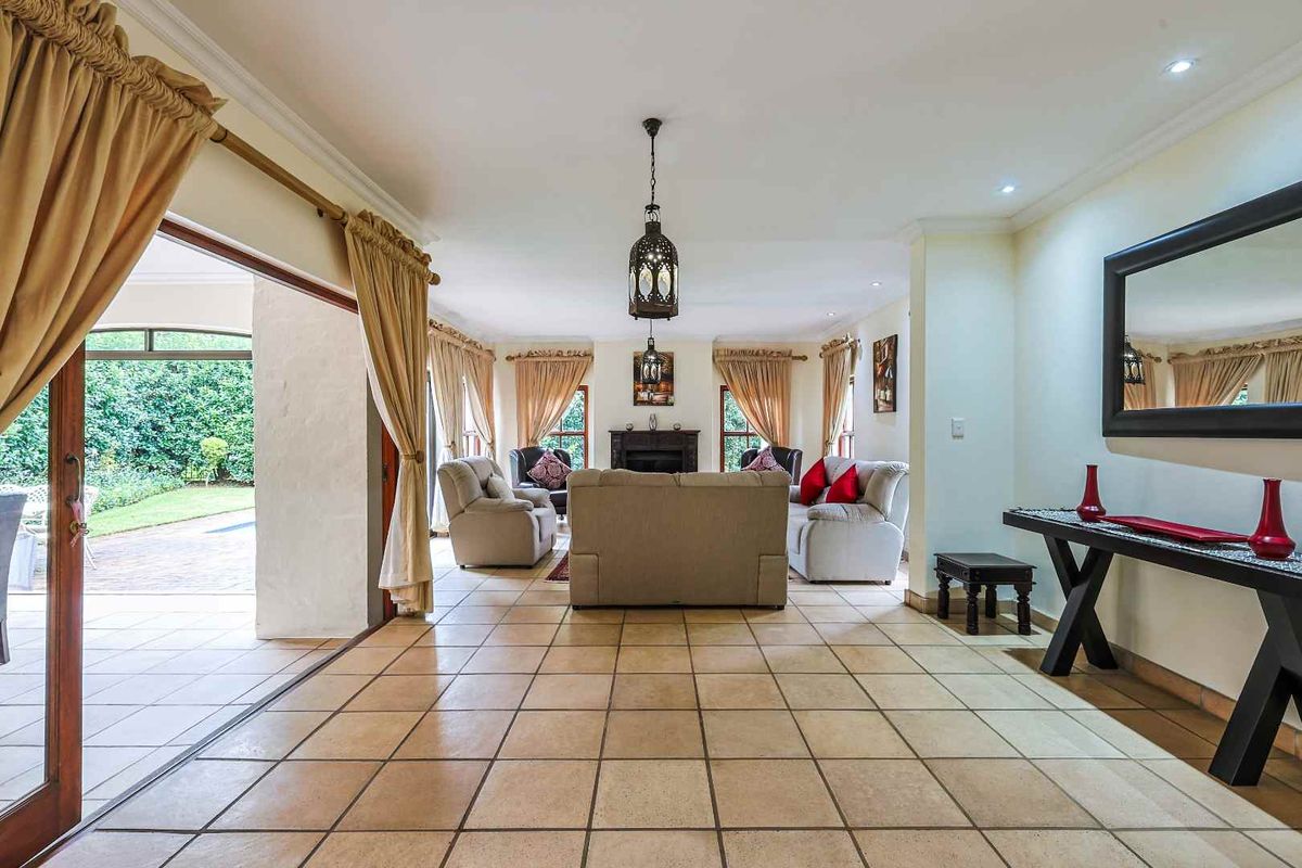 Spacious living room featuring tiled flooring, a built-in fireplace, and large sliding doors providing seamless access to the outdoor patio and garden area.