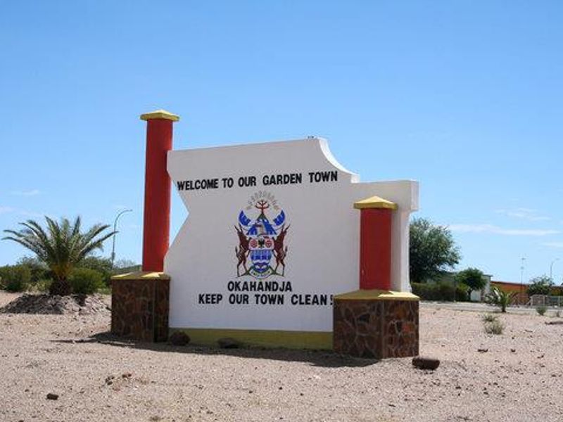 A town entrance sign featuring masonry pillars and stone cladding, situated on a vacant commercial plot.