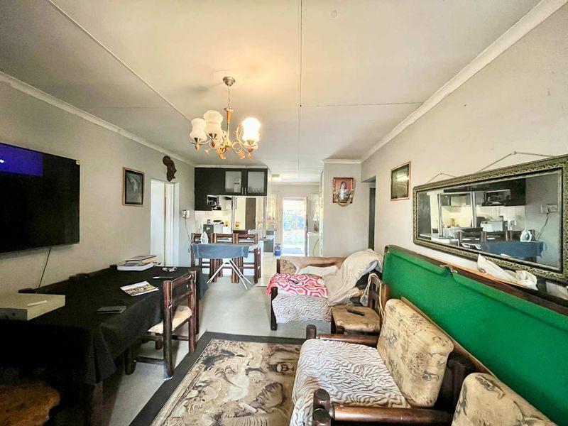 Open plan living and dining area featuring tiled flooring and ceiling cornice, leading through to the kitchen area.