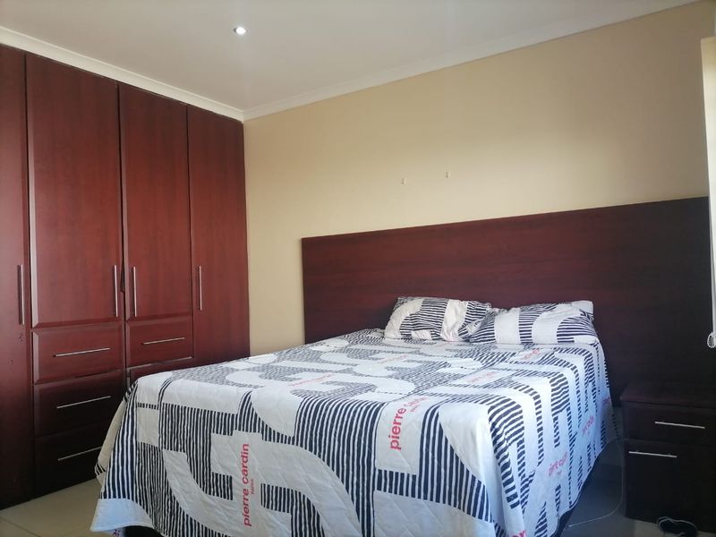 A bedroom featuring dark wood built-in cupboards and a matching integrated headboard, providing functional storage and a cohesive design aesthetic.