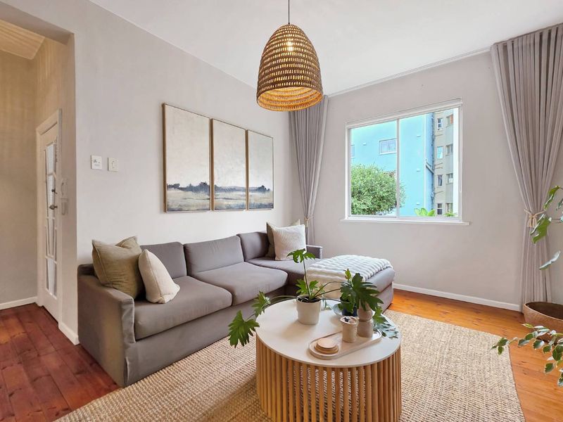 A bright and inviting living room featuring warm timber flooring, neutral wall tones, and a large sliding window that allows for natural light.