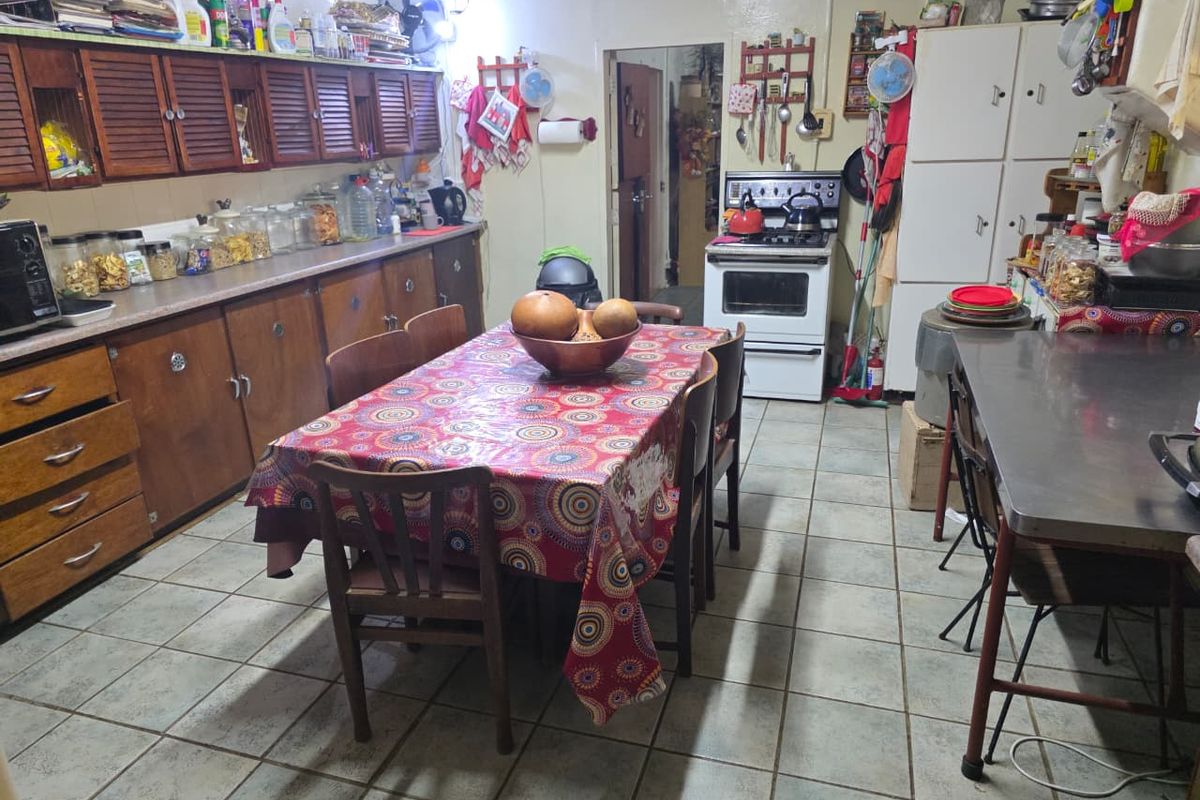 A functional kitchen featuring wooden cabinetry, a freestanding oven, and tiled flooring, offering a practical layout for daily meal preparation.