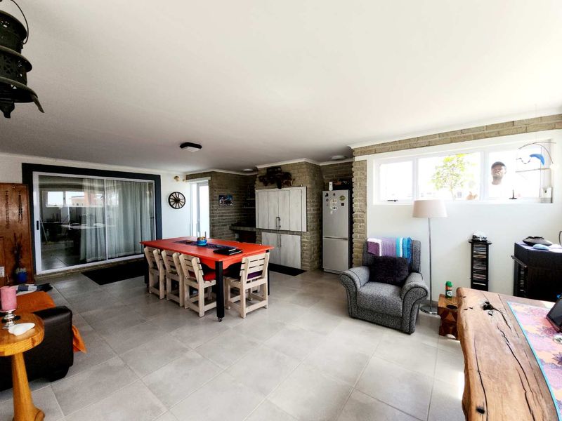 Spacious open-plan living and dining area featuring tiled floors, exposed brick accents, and large sliding doors providing natural light.