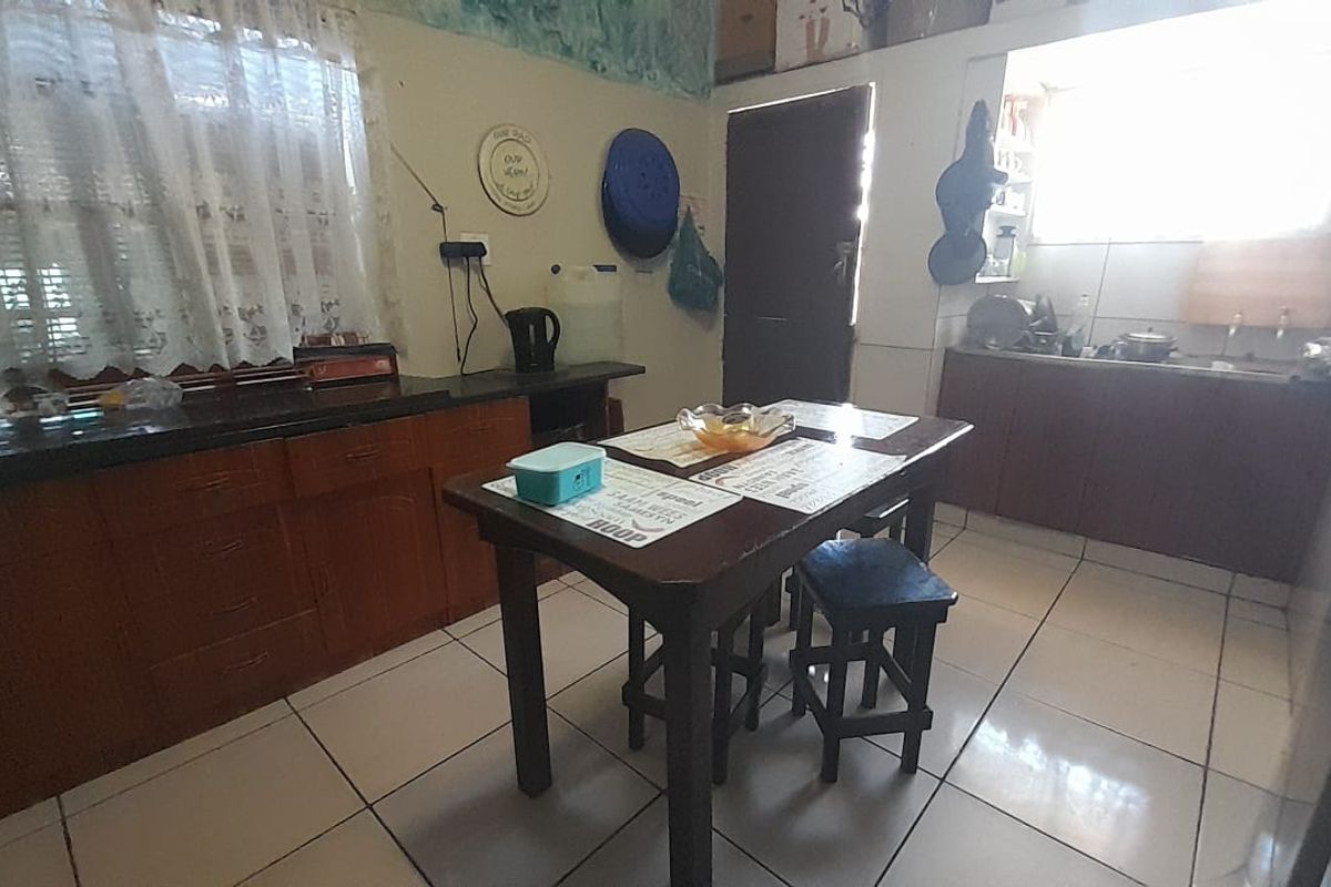 A functional kitchen space featuring wooden cabinetry, dark countertops, and tiled flooring, offering a practical layout for daily meal preparation.