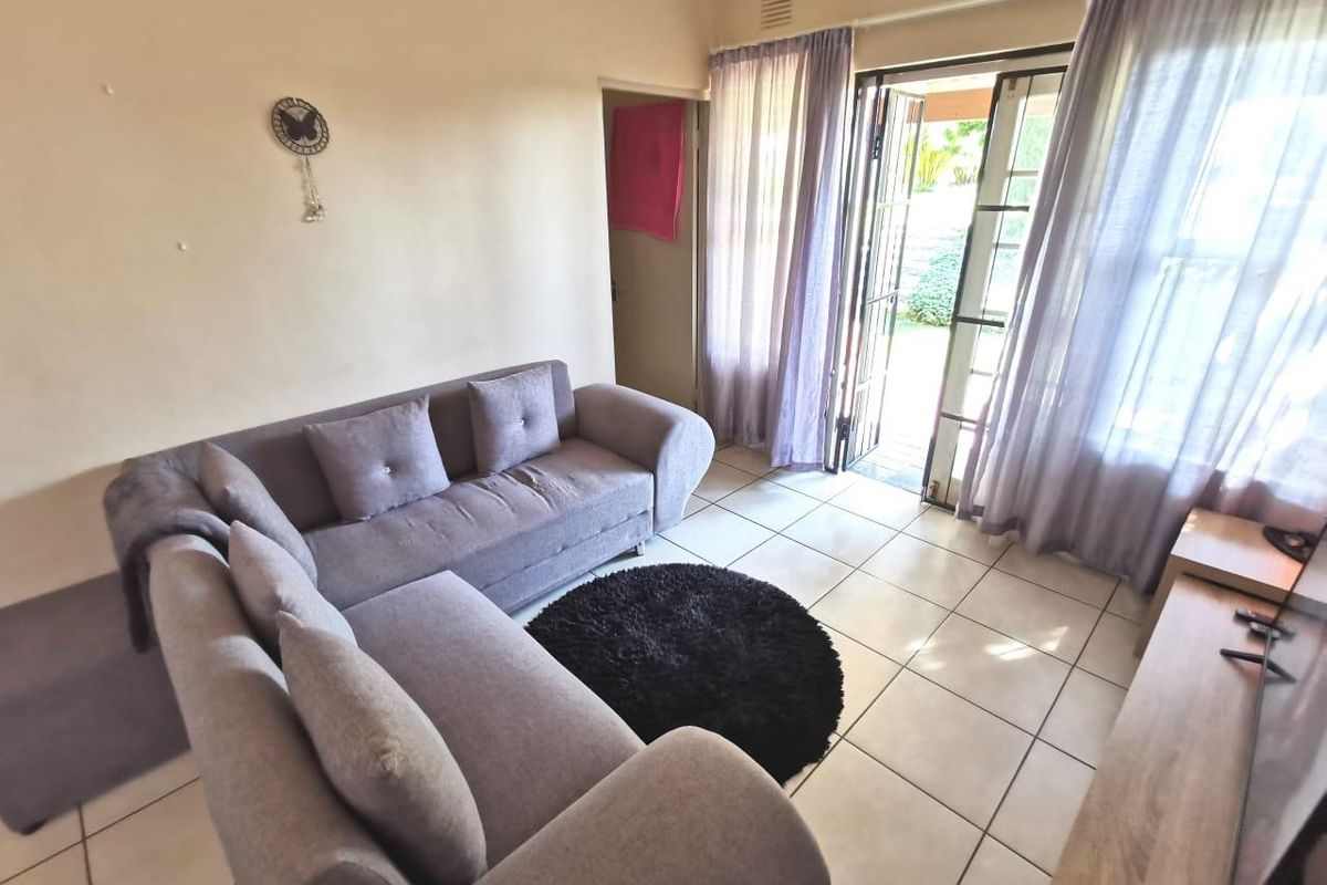 A living room featuring tiled flooring and a sliding glass door providing access to the outdoor area.