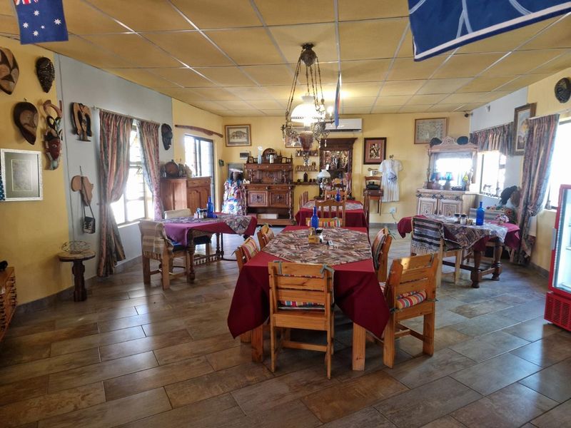 Spacious dining area featuring tiled flooring, a suspended ceiling, and a central chandelier, suitable for lodge-style hospitality or event hosting.