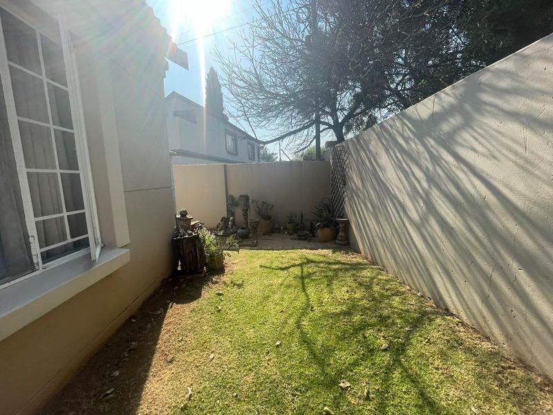 A private rear garden area featuring a small lawn, paved section, and high boundary walls for privacy.