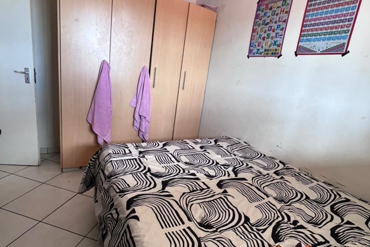 A bedroom featuring built-in wooden cupboards and tiled flooring.