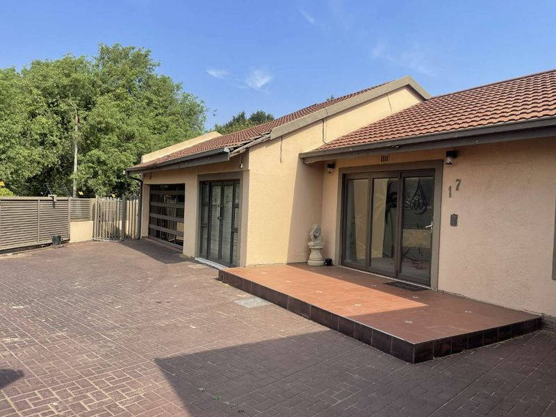 Front exterior view of a single-story house featuring a paved driveway, tiled porch, and sliding glass door entrance.