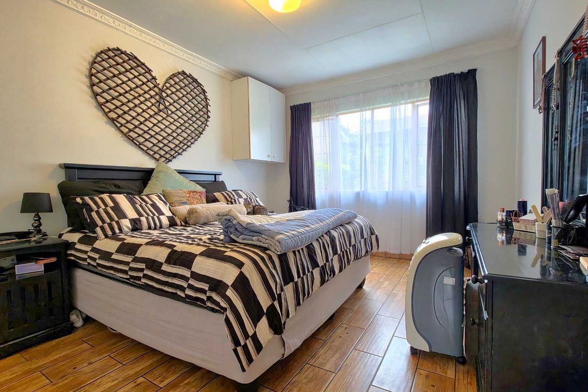A bedroom featuring wood-look tiled flooring, decorative ceiling cornicing, and a built-in wall cabinet.