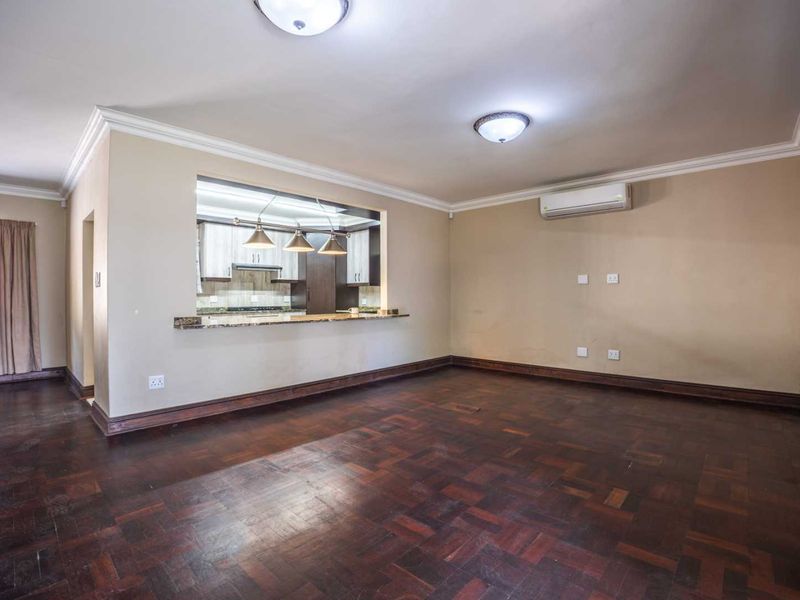 Spacious open-plan living area featuring classic parquet flooring, a granite breakfast bar, and a convenient pass-through to the kitchen.