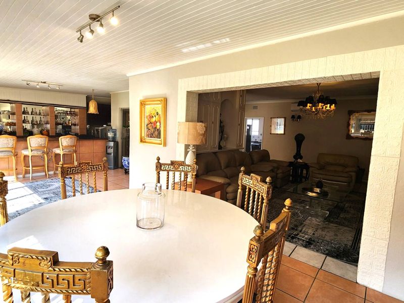Spacious open-plan living area featuring a built-in bar, tiled flooring, and a distinctive tongue and groove ceiling, connecting the dining and lounge spaces.