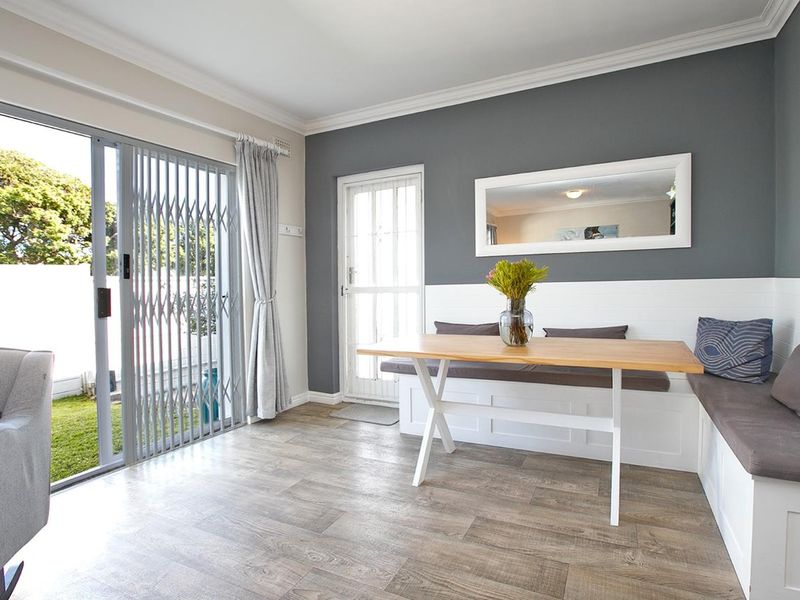 A bright dining area featuring built-in bench seating, laminate flooring, and a sliding glass door providing direct access to the garden.