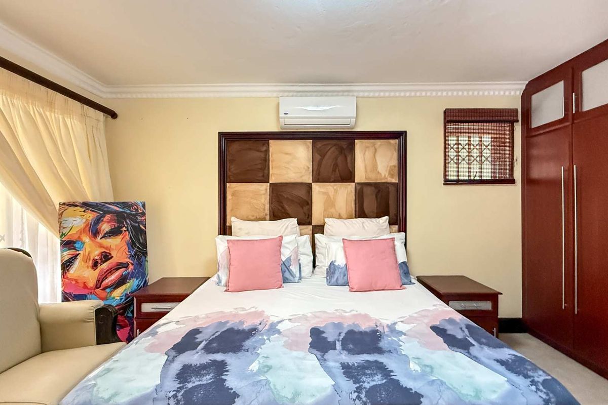 A well-maintained bedroom featuring built-in wooden cabinetry, a wall-mounted air conditioning unit, and decorative crown molding.