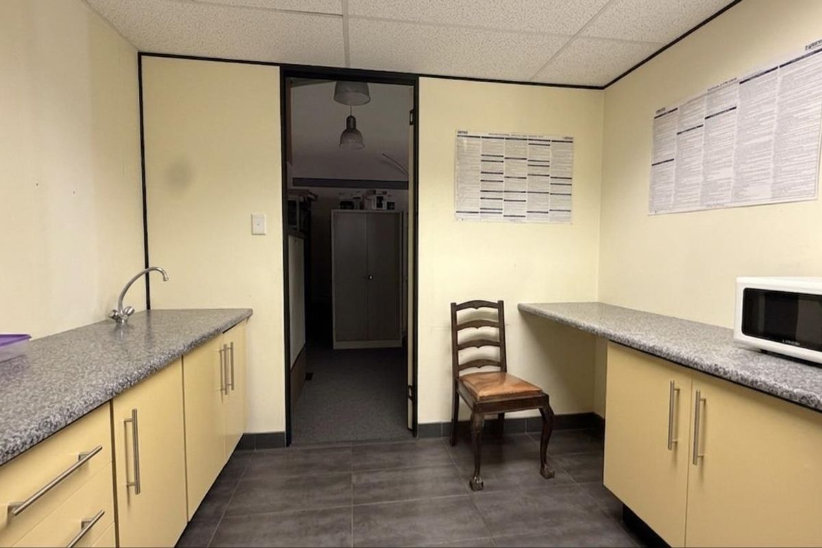 A functional office kitchenette featuring laminate countertops, built-in cabinetry, and a sink, providing a convenient space for staff refreshments.