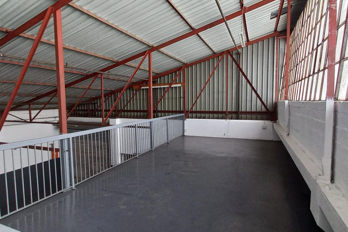 An open-plan industrial mezzanine level featuring exposed steel trusses, metal roofing, and large steel-framed windows, providing a versatile elevated workspace.