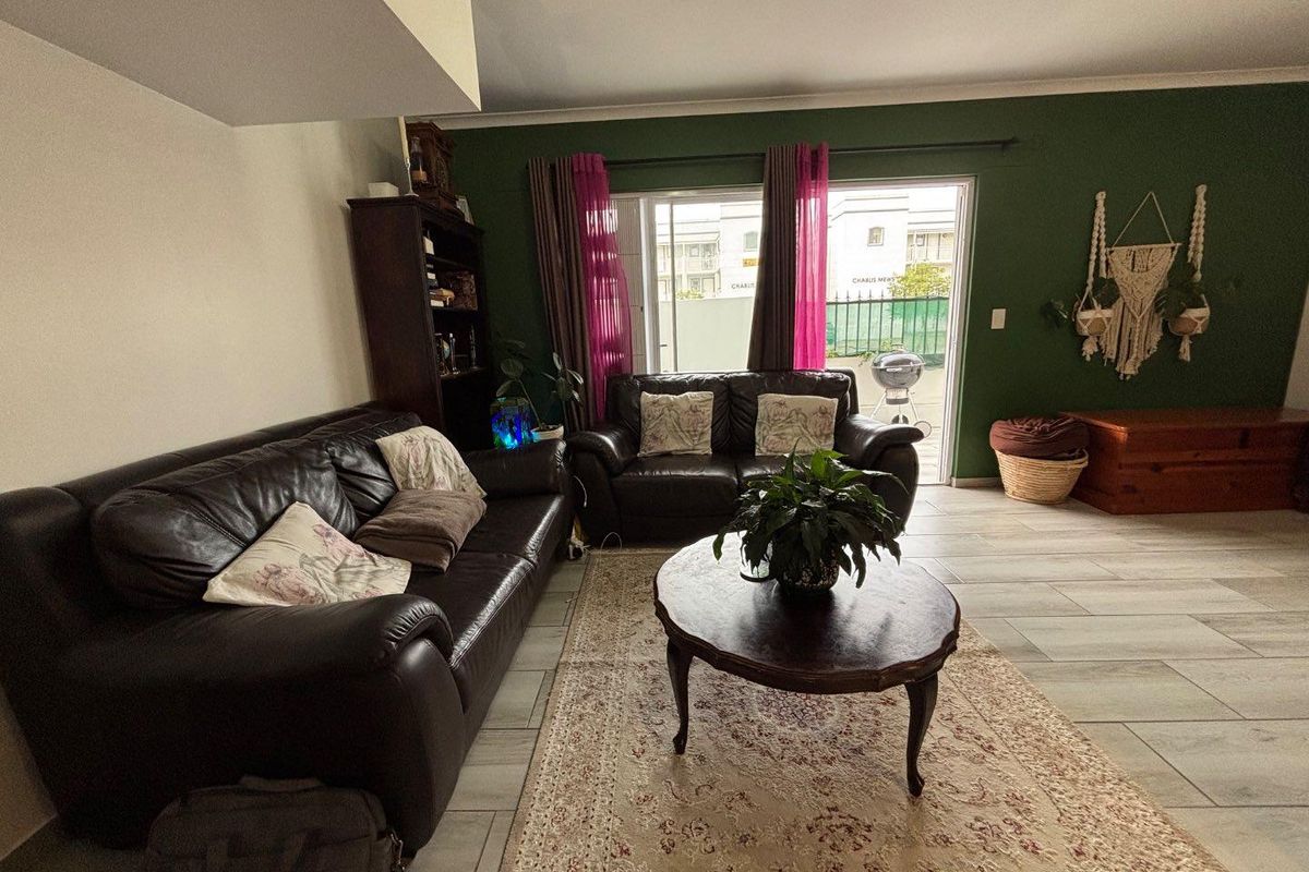 A living room featuring tiled flooring and a sliding glass door providing access to the outdoor area.