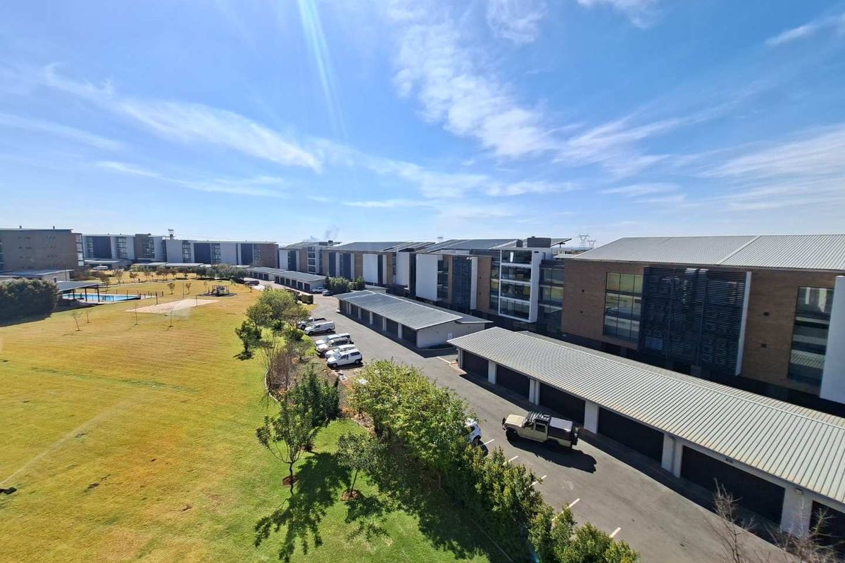 Aerial view of the apartment complex featuring communal green spaces, paved driveways, and covered carport parking facilities.
