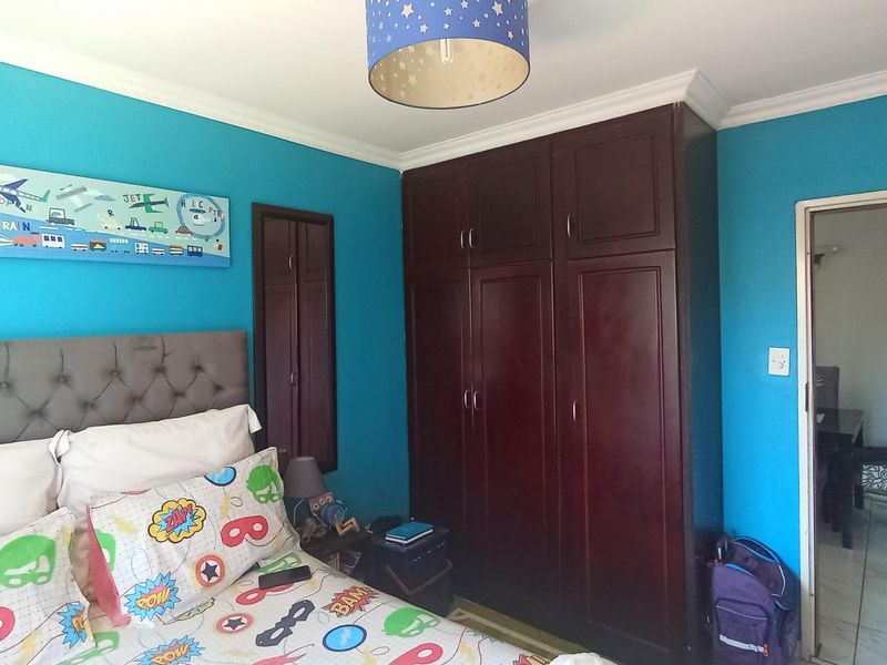 A bedroom featuring dark wood built-in cupboards and crown molding, finished with bright blue wall paint.