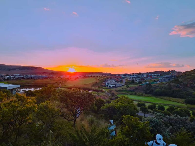 A scenic sunset view overlooking a residential estate, golf course, and surrounding natural landscape.