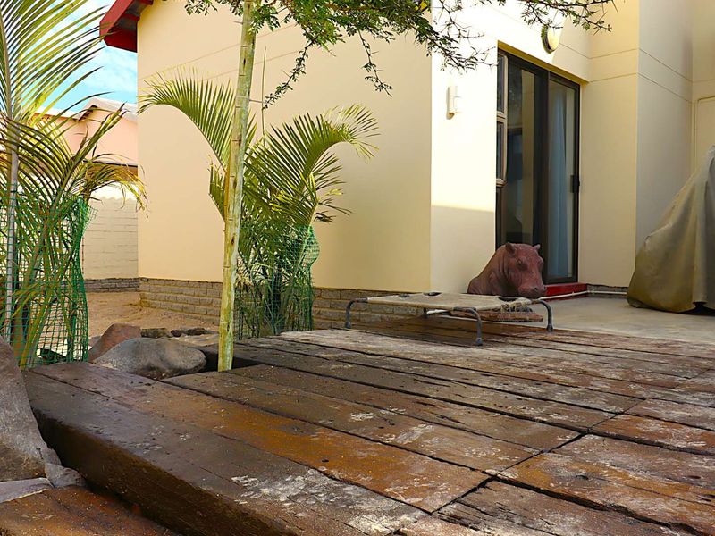 Outdoor patio area featuring a timber deck, sliding glass door access, and exterior wall lighting.
