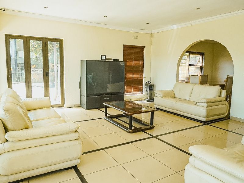 Spacious living room featuring large format tiled flooring, an elegant archway leading to an adjacent room, and sliding glass doors providing natural light.