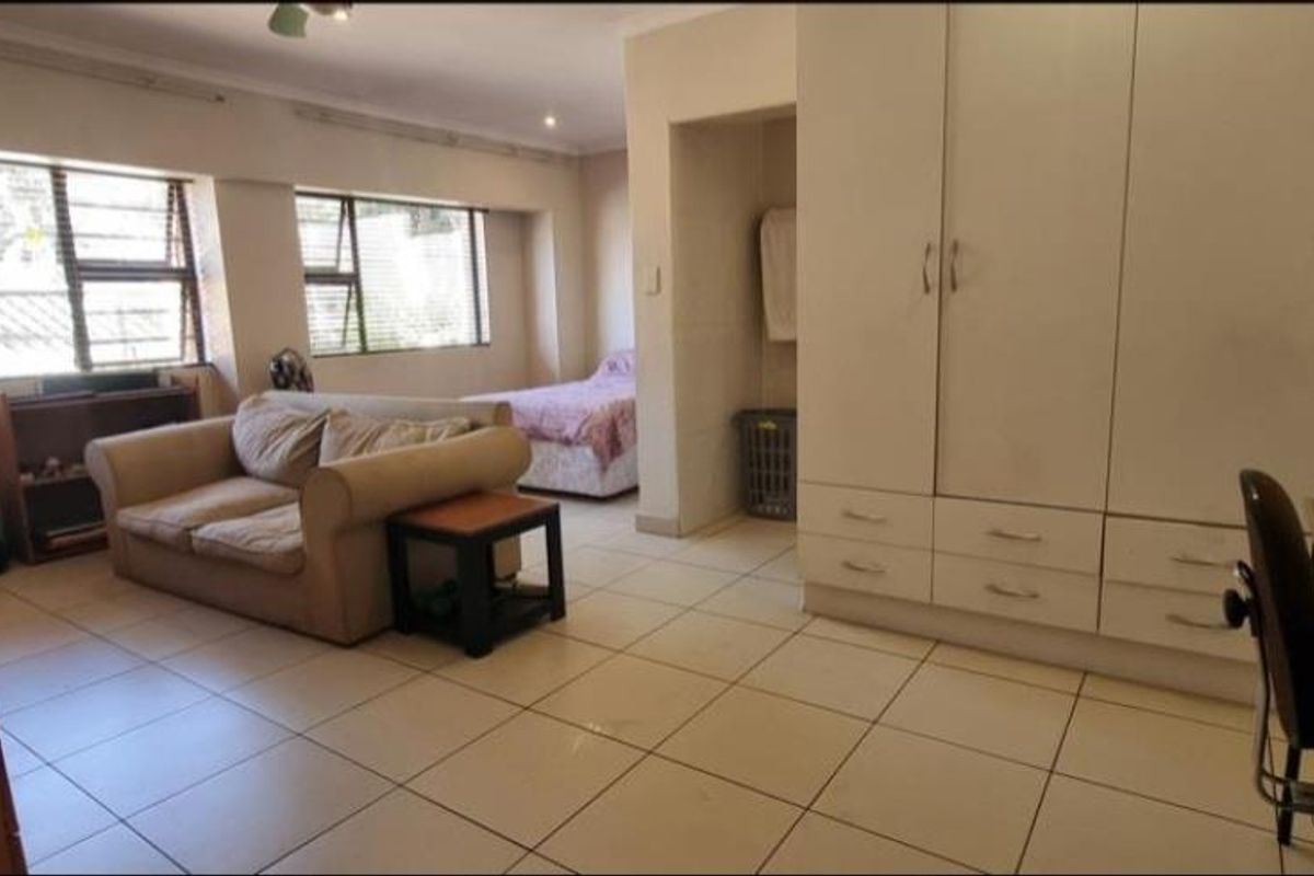 Spacious bedroom featuring large built-in cupboards, tiled flooring, and ample natural light through multiple windows.