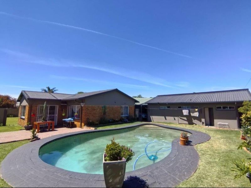 Outdoor pool area featuring a curved swimming pool with brick paving, set against a brick and metal-roofed residential structure.
