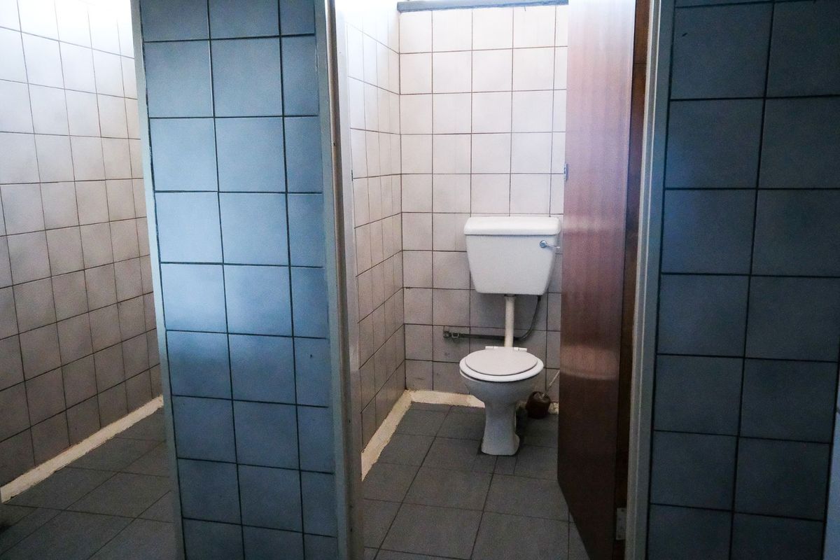 A functional office restroom featuring tiled walls and flooring with a standard toilet suite.