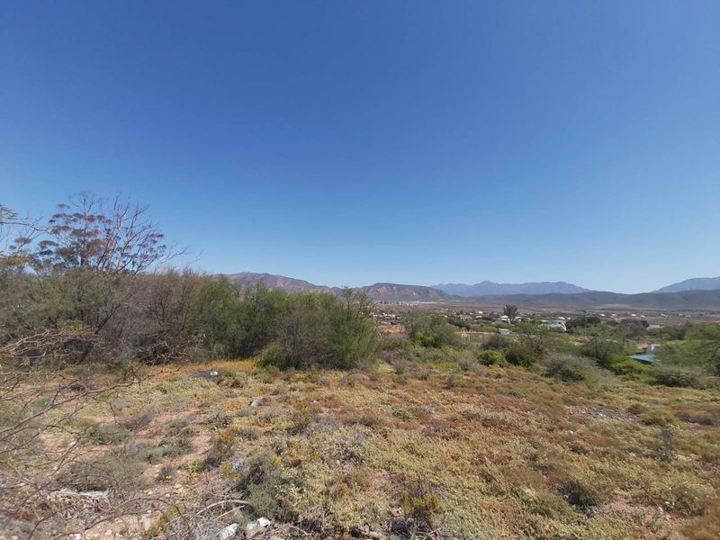 A wide-angle view of the vacant residential land featuring natural vegetation and distant mountain scenery.