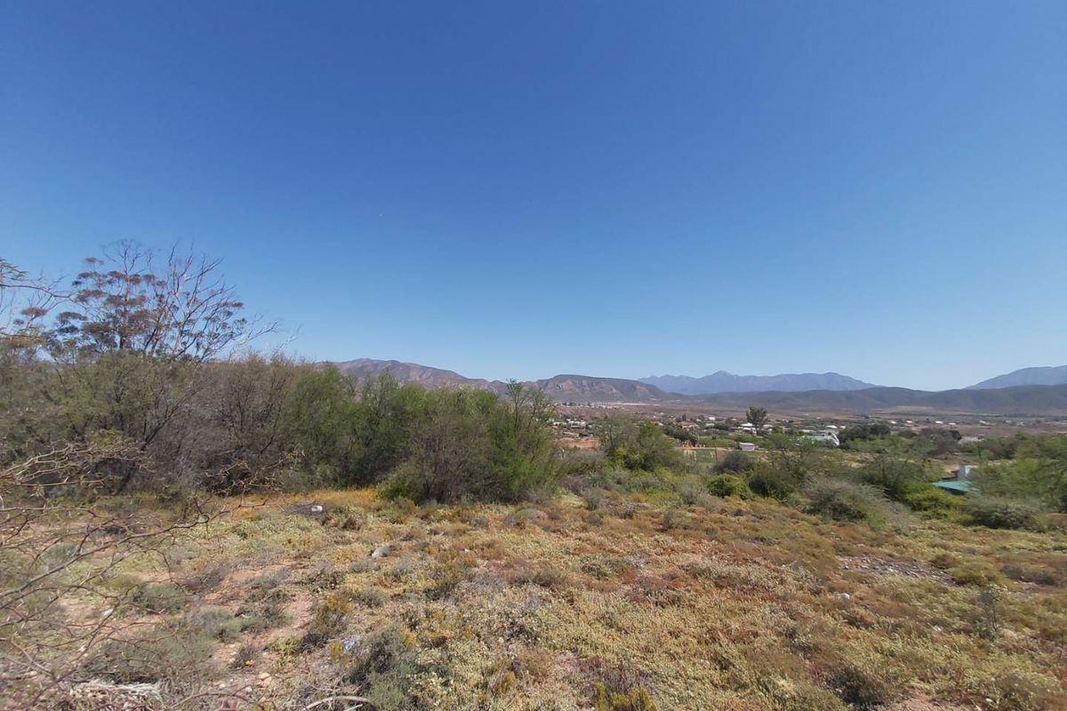 A wide-angle view of the vacant residential land featuring natural vegetation and distant mountain scenery.
