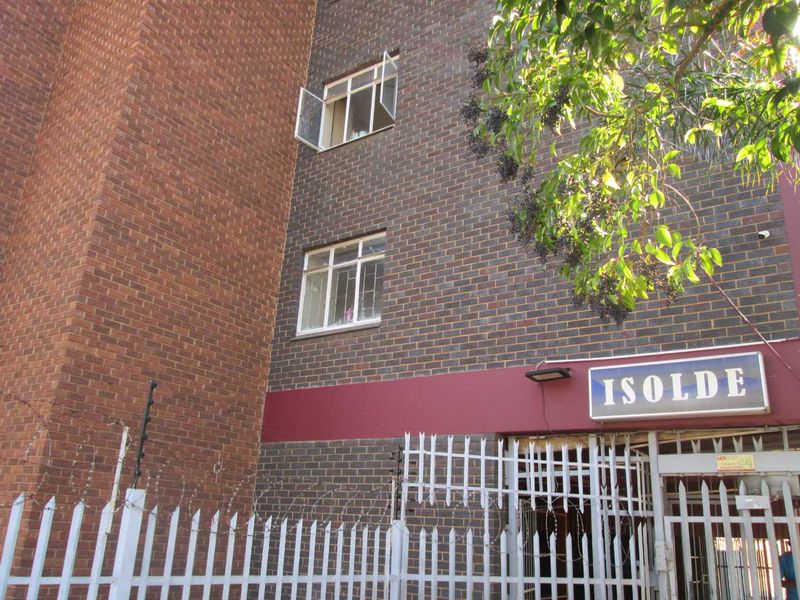 Exterior view of the Isolde apartment building featuring a brick facade, security fencing, and gated entrance.