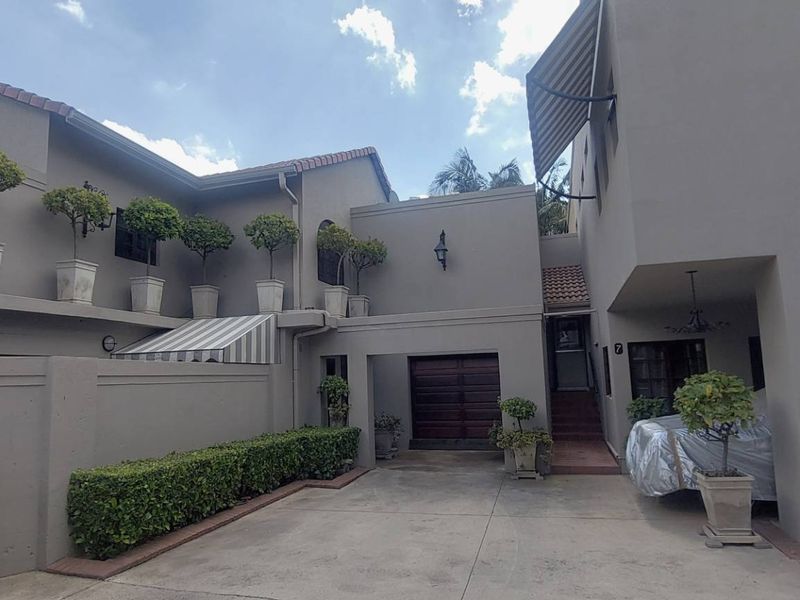 Front elevation of a townhouse featuring a concrete driveway, integrated garage, and exterior wall-mounted lighting.