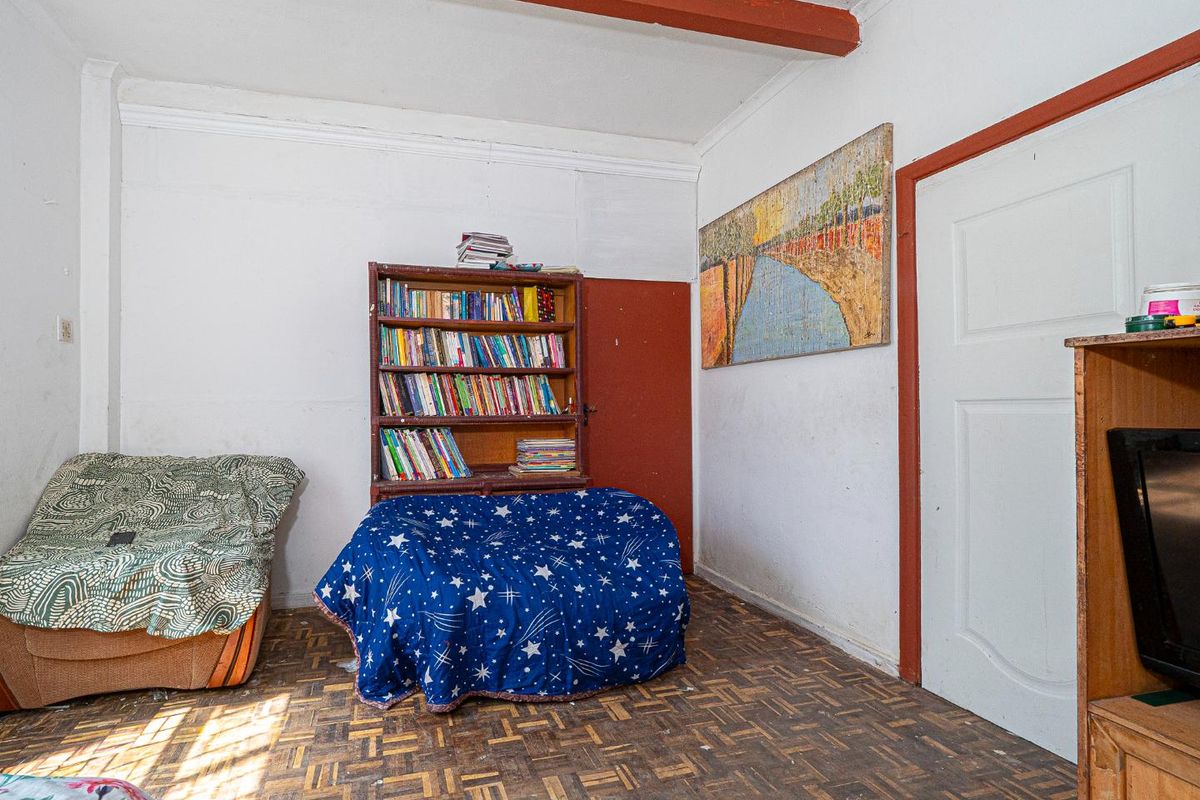 A living room featuring original parquet flooring, exposed ceiling beams, and traditional door frames, offering a blank canvas for renovation and modernization.