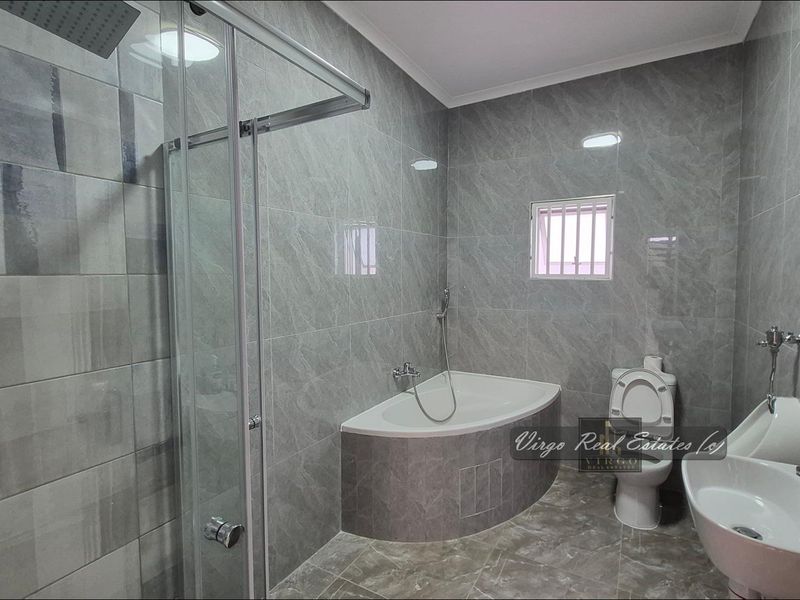 Modern bathroom featuring grey marble-effect wall and floor tiles, a walk-in shower, a built-in bathtub, and a contemporary washbasin.